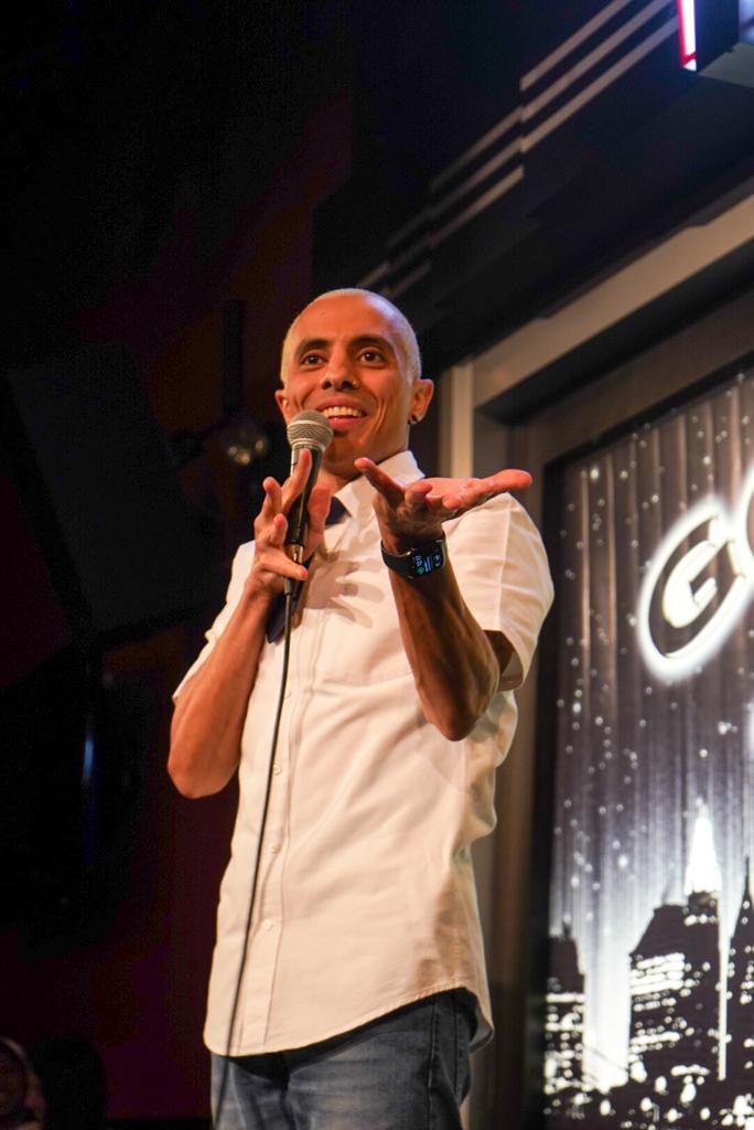 Eman Morgan performing stand-up in a white shirt